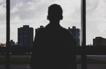 joven mirando hacia los edificios por la ventana en dia nublado