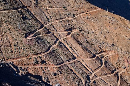 High-Angle View of Winding Mountain Roads and Terraced Farmland on a Steep, Arid Slope in the Atlas Mountains, Morocco