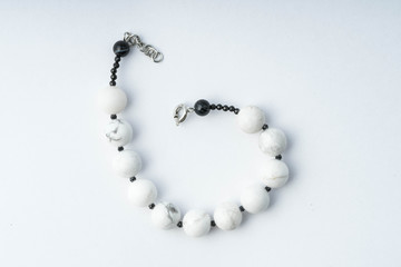 Handmade bracelet made of cacholong, black spinel and agate on a white background