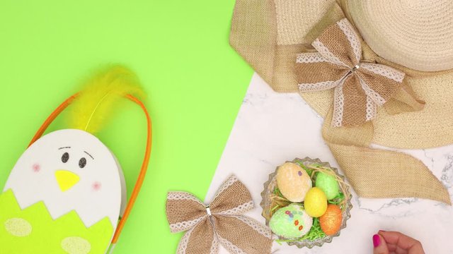 Green Easter decoration appear on marble background and woman's hand put bow on hat - Stop motion 