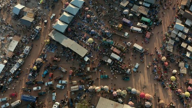Aerial top down drone shot of African market in Ghana. A big group of Africans trading and walking with buckets on heads.