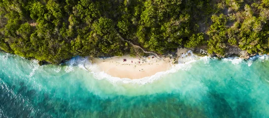 Foto op Aluminium Uitzicht van bovenaf, prachtige luchtfoto van sommige toeristen die zonnebaden op een prachtig strand badend in een turquoise ruwe zee tijdens zonsondergang, Green Bowl Beach, Zuid-Bali, Indonesië. © Travel Wild