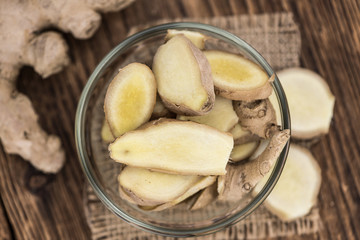 Some Ginger Slices on a vintage wooden table (selective focus; close-up shot)