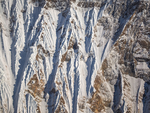 Abstract Close-up of Steep, Snow-Covered Himalayan Mountain Slope with Strong Light and Shadow Contrast and Exposed Brown Rocks, Nepal