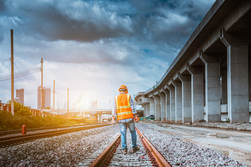 Naklejka premium A senior engineer under inspection and checking construction process railway and checking work on railroad station platform .Engineer wearing safety uniform and safety helmet in work.