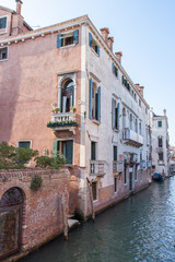 Fototapeta na wymiar Old Venetian Building by Canal with Brick Wall at Water Level