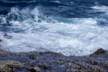 Blue atlantic ocean, white foam and volcanic rock