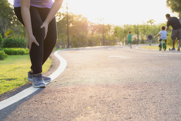 Knee Injuries. Young sport woman holding knee with her hands in pain after suffering muscle injury during a running workout on Running Track. Healthcare and sport concept.