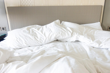 Fototapeta na wymiar White pillow with blanket on bed unmade