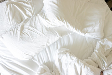 White pillow with blanket on bed unmade