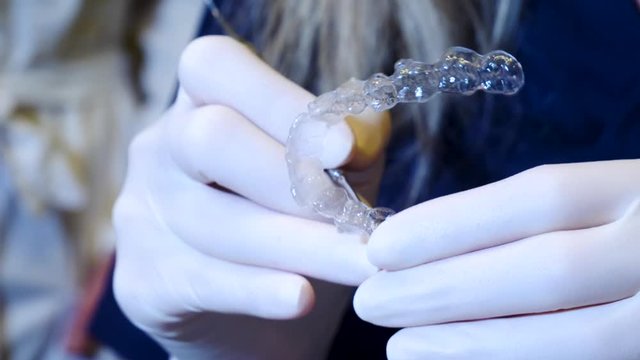hands close-up of an orthodontist handling an invisalign aligner
