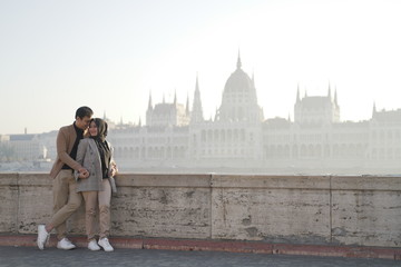 a couple posing against a river background and beautiful city buildings of budapest