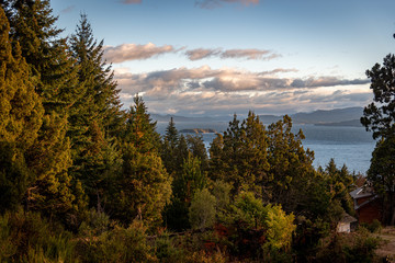 Obraz na płótnie Canvas Beautiful cloudy sunset view of the lake Nahuel Huapi, its islands and mountains in the background, surrounded by forests in Bariloche, Argentina
