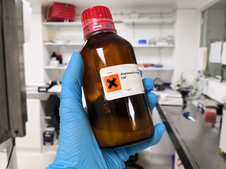 Scientist holding an amber bottle with an irritating and dangerous liquid in a laboratory