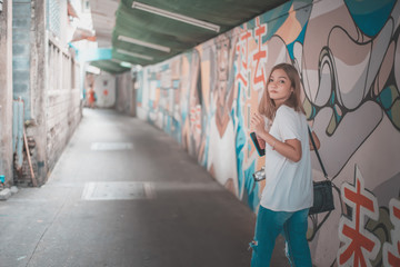 Portrait of young beautiful asian woman was walking along the graffiti wall
