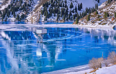 Water height measure tools in the mountain lake; texture and patterns of ice on the serene water surface of a mountain lake; Big Almaty lake in Kazakhstan
