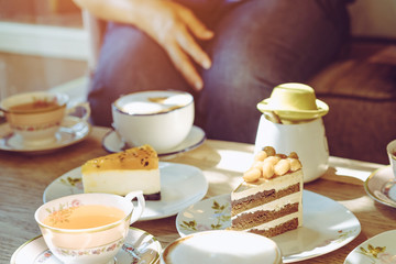 Happiness female friends meeting and drinking tea or coffee with cakes together at cafe in the afternoon. People, leisure and communication concept. Selective focus.