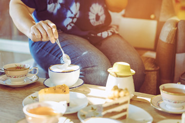 Happiness female friends meeting and drinking tea or coffee with cakes together at cafe in the afternoon. People, leisure and communication concept. Selective focus.