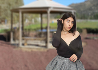 Beautiful young woman with beautiful eyes and lips posing in the park in front of one kiosk