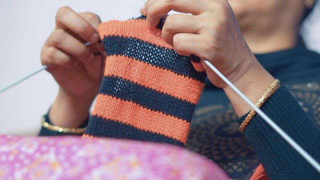 Woman knitting scarf with red and black wool. 4K Footage from below of knit work tie-up hand work