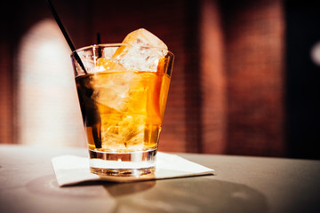 A close up of a glass of whiskey on a table at a bar at night 