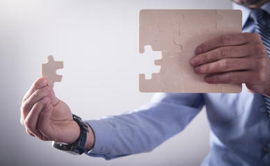 Businessman assembling jigsaw puzzle. Business