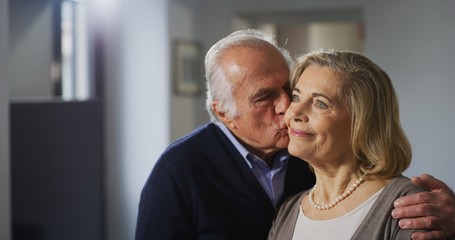 Close up of a lovely senior husband is giving a kiss to his wife as a sign of forever love at home.