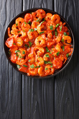Mediterranean food spicy shrimp in tomato sauce close-up in a plate. Vertical top view