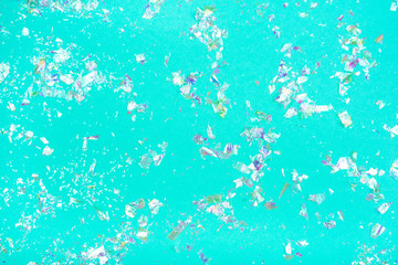 Fototapeta na wymiar Pearl confetti on mint background. Flat lay, top view.