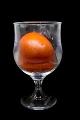 Tomato in the glass on black background
