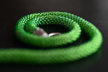 Light green beaded necklace on a dark surface close-up. Fashion background