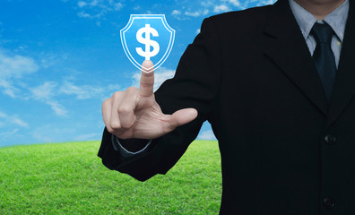 Businessman pressing dollar with shield flat icon over green grass field with blue sky, Business money insurance and protection concept