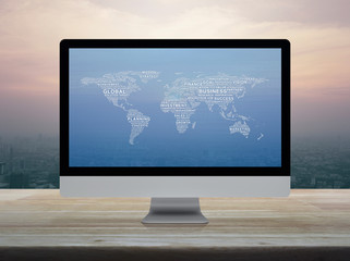 Global business words world map on desktop modern computer monitor screen on wooden table over city tower and skyscraper at sunset sky, vintage style, Global business online concept, Elements of this 