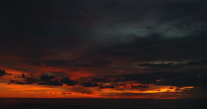 Ocean panorama. Dark orange clouds day to night sky. Dramatic sunset over storm clouds. Beautiful red color sky. Red purple orange blue pink sunset cloud background. Concept holiday in the tropics.