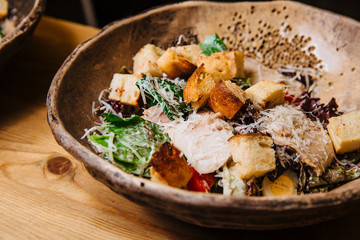 Salad of chicken breast slices, green salad, Parmesan cheese and croutons.