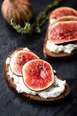 Tasty rye bread toast with cream cheese and fresh ripe figs. Healthy appetizer or snack. Black...