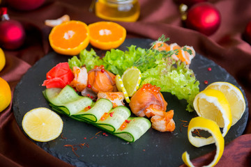 Cold dish of salmon and shrimp with vegetables on a black plate in the interiors of the restaurant. Restaurant menu.