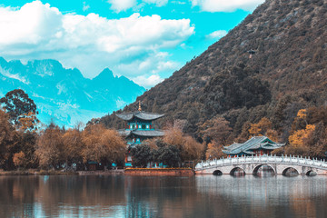 Obraz premium Beautiful view of the Jade Dragon Snow Mountain and the Suocui Bridge over the Black Dragon Pool in the Jade Spring Park, Lijiang, Yunnan