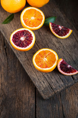 Sliced Sicilian Blood oranges fruits over old dark wooden background. Top view.