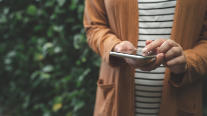 Young woman using mobile smart phone in nature background.