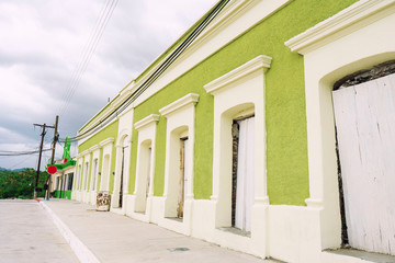 Traditional Green wall with wooden door house of Mexican on the road with street cable light over clouds sky background.