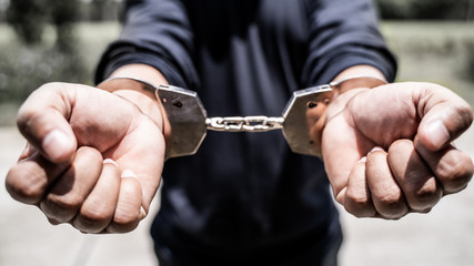 Male hands arrested with handcuffs in Criminal concept.