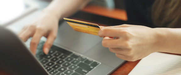 Close up hand of woman holding credit card shopping on website.