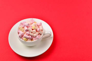 Cup with marshmallow on a red background. Copy space.