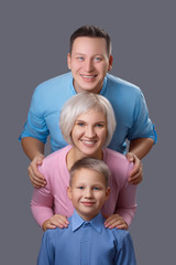 Vertical creative portrait of a cute beautiful smiling happy European family against a gray background in the studio