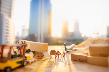 Miniature people: Worker loading box to truck container on world map with blurred city scape using as background business shipping, rent container, worldwide transportation concept.