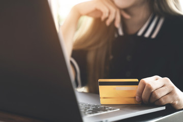 Close up hands of woman holding credit card shopping on website.