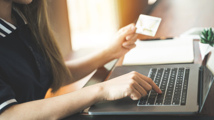 Young woman using credit card shopping online with laptop computer.