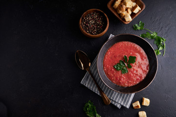 Traditional Spanish tomato soup Gazpacho with spice in black bowl on dark stone background Copy...