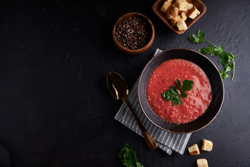 Traditional Spanish tomato soup Gazpacho with spice in black bowl on dark stone background Copy space